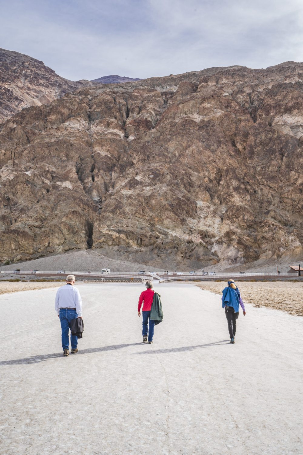 The image shows three senior adults hiking in Badwater Basin in Death Valley